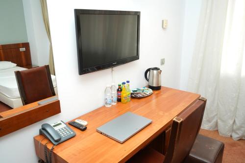 a desk with a laptop and a phone and a television at Hotel Bliss Aksu in Bucharest