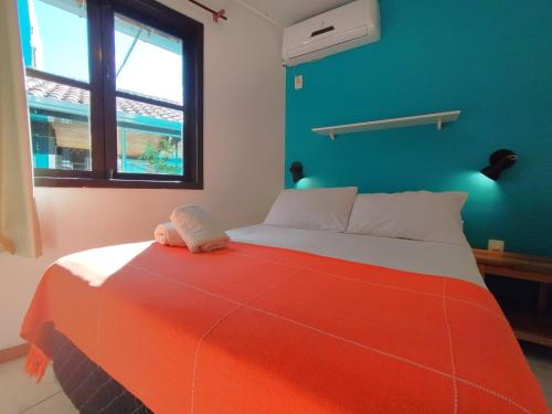 a bedroom with a bed with an orange blanket at Residencial Vila do Sol, Apartamentos com pé na areia in Bombinhas