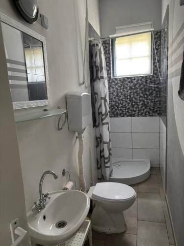 a white bathroom with a toilet and a sink at Sunset Beach House in Fonyód