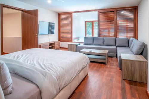 ein Schlafzimmer mit einem Bett und einer Couch in der Unterkunft Luxury 3 Bedroom Condo - Infinity Pool - AWA Residences - Condo Anahuac 110 in Playa del Carmen