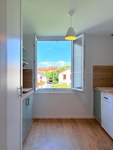 une cuisine avec une grande fenêtre offrant une vue dans l'établissement Biarritz proche Côte des Basques - T2 rénové, à Biarritz