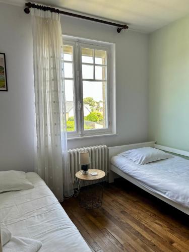 - 2 lits dans une chambre avec une fenêtre et une table dans l'établissement Petit Kennedy Maison 4 personnes Rochebonne, à Saint-Malo