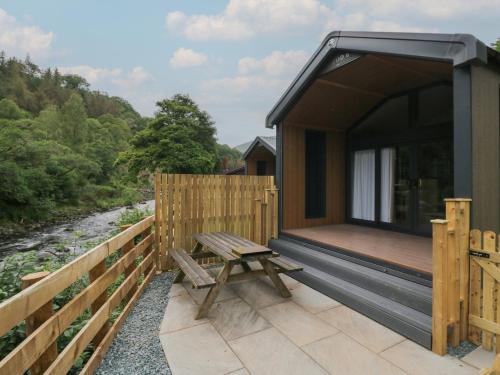 a wooden cabin with a wooden bench on a deck at Lingy Luxury Family Pod in Keswick
