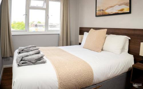a bedroom with a bed with white sheets and a window at The Watling Inn in Nuneaton