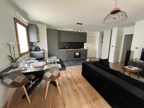 un salon avec un canapé noir et une table dans l'établissement Cosygreen77- modern apartment with garden and parking, 7mns by car from Disneyland, à Magny-le-Hongre
