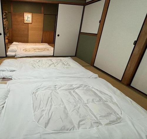 a large white bed in a room with sliding doors at kyoto next door in Otsu