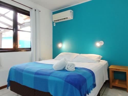 a blue bedroom with a bed with towels on it at Residencial Vila do Sol, Apartamentos com pé na areia in Bombinhas
