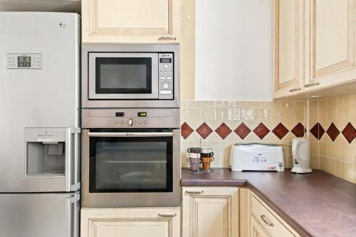 une cuisine avec des appareils en acier inoxydable et des armoires blanches dans l'établissement Maisonnette au calme et à 3mn du centre de Sanary - climatisée - proche portissol, à Sanary-sur-Mer