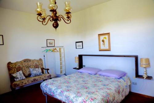 パンツァーノにあるLittle B&B Della Pieveのベッドルーム1室(ベッド1台、ソファ、シャンデリア付)