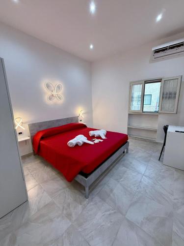 a bedroom with a red bed with two towels on it at Core Salentino Rooms in Campomarino