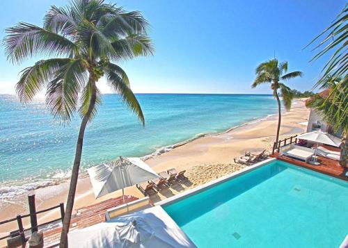 a swimming pool next to a beach with palm trees at Luxury 3 Bedroom Condo - Beachfront Complex at Mareazul - Buena Vida in Playa del Carmen