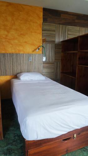 a bedroom with a large bed with white sheets at Madre Tierra Hostal in Puerto Escondido