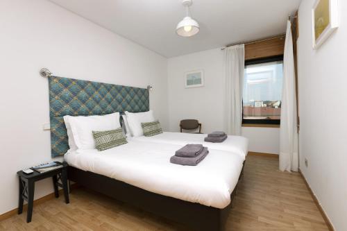 a bedroom with a large white bed with a blue headboard at LV Premier Marques MQ2 in Porto