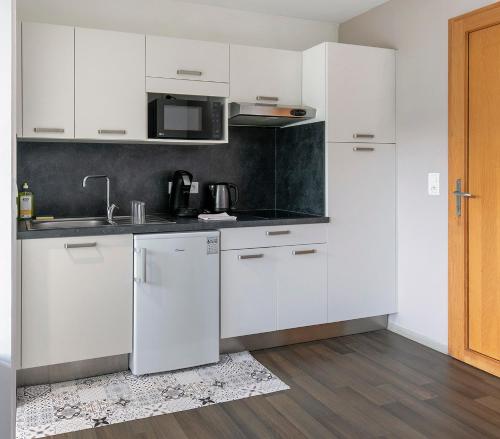 La cuisine blanche est équipée d'un évier et d'un réfrigérateur. dans l'établissement Apparts Confort 87, à Limoges