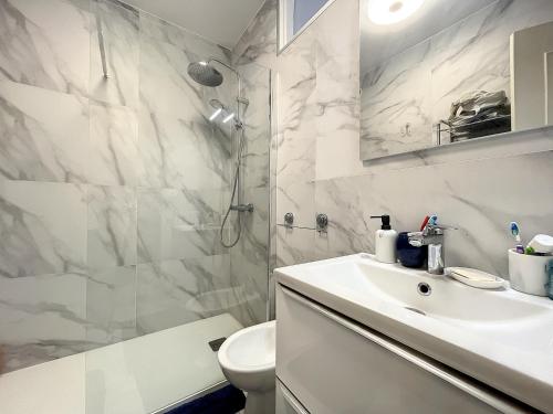 une salle de bain blanche avec un lavabo et une douche dans l'établissement Un Coin de Plage, à Antibes