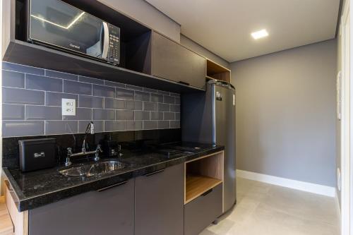 a kitchen with a sink and a microwave at 360 Mirant Vila Madalena in Sao Paulo