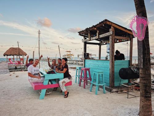 Un grupo de personas sentadas en una mesa en la playa. en Barefoot Beach Belize, en Caye Caulker