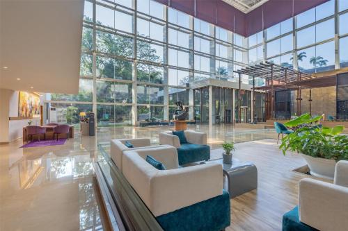 a large lobby with couches and chairs and windows at Radisson Blu Plaza Hotel Hyderabad Banjara Hills in Hyderabad