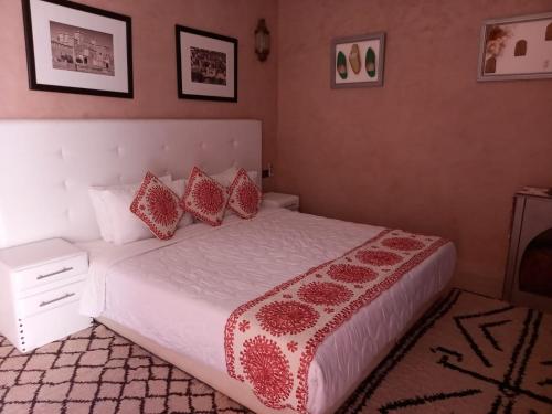 a bedroom with a white bed with red pillows at Riad Ouarzazate in Ouarzazate