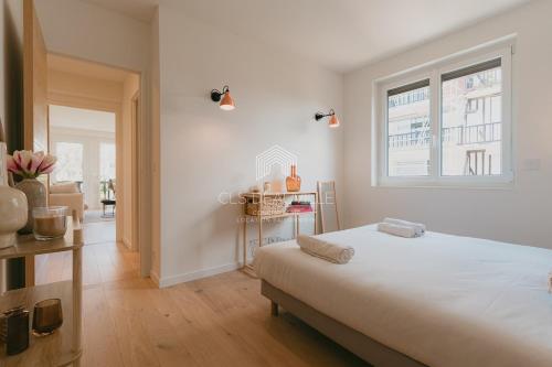 une chambre blanche avec un grand lit et une fenêtre dans l'établissement Les Prairies de Deauville Plein centre CLS, à Deauville