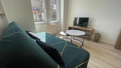 un salon avec un canapé vert et une table dans l'établissement maison de ville, à Saint-Pierre-de-Plesguen