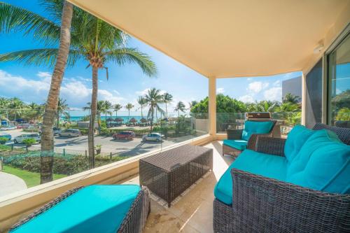 a balcony with a view of the ocean and palm trees at Ocean View Condo - 2 Bedrooms - at The Elements Condos - Castillo de Arena in Playa del Carmen
