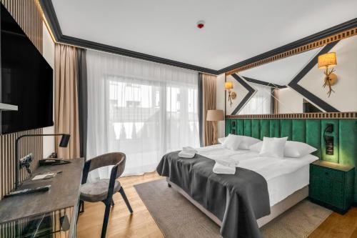 ザコパネにあるRysy Boutique Aparthotelの大きなベッドと机があるホテルの部屋