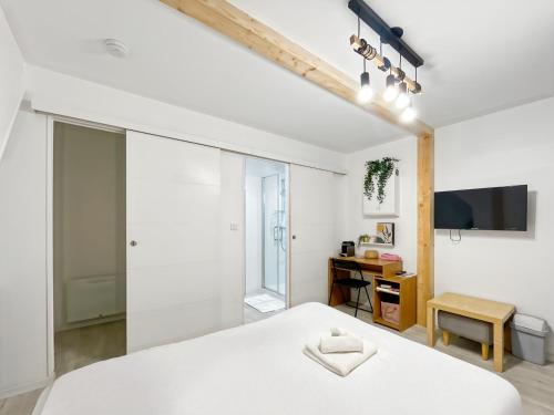 une chambre avec un lit blanc et une télévision dans l'établissement Opale - Centre Historique - Proche gare - Calme, à Rennes