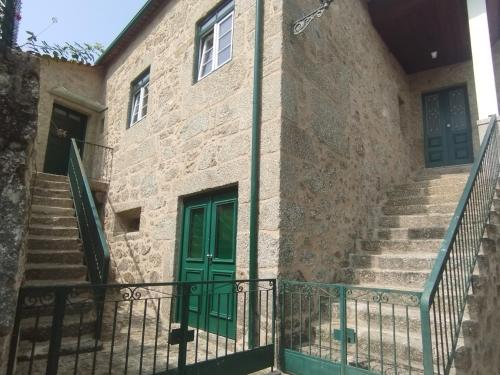a building with stairs and a green door at Casa do Forno in Ponte da Barca