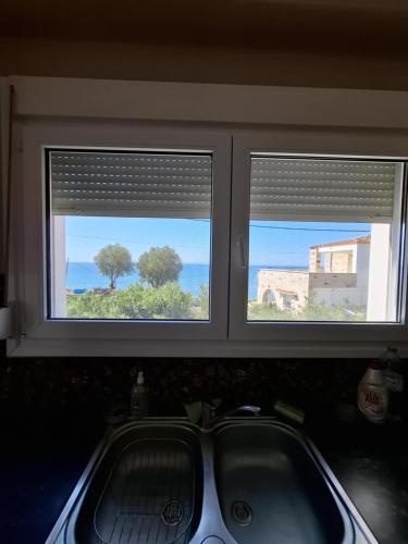 a window above a sink with a view of the ocean at Myriam&Ioanna Seaside Apartment in Chios