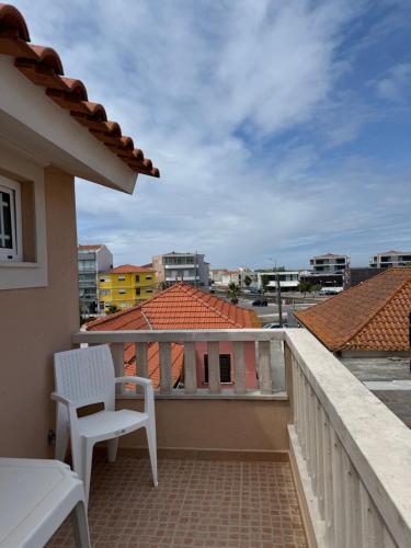 a balcony with a white chair and a view of the city at Casa da vala in Praia de Mira
