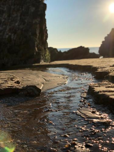 a rocky beach with the sun in the background at Parador de Mazagón in Mazagón