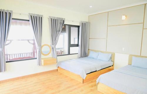 una camera da letto con due letti e due finestre di The Sunset a Phan Thiet