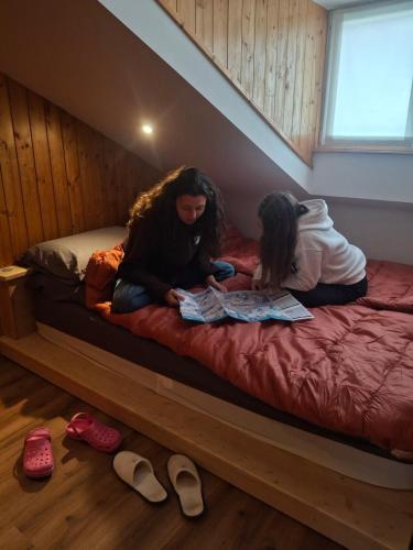 two girls sitting on a bed reading a magazine at Inner Holiday Dolomites 5 in Dimaro