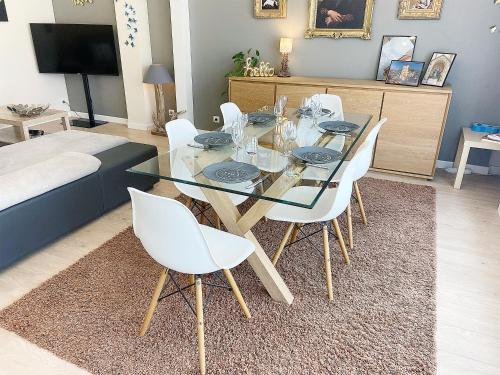 a dining room with a glass table and white chairs at Chez Clém - 3 chambres - garage privé - wifi - Netflix in Reims