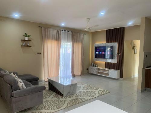 a living room with a couch and a tv at Cozy 2BR Bungalow Senegambia in Serekunda