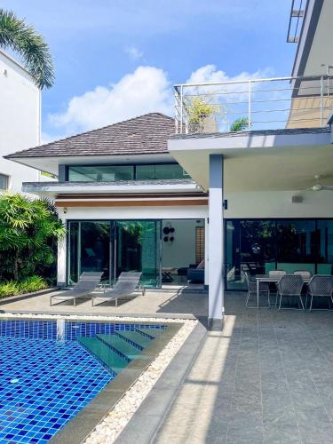 a house with a swimming pool next to a house at Tropical Haven Villa 4-Bedroom Private Pool Butler Choeng Thale Phuket in Bang Tao Beach
