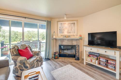 a living room with a television and a fireplace at Ocean Shores Condo with Balcony Less Than 1 Mi to Beach! in Ocean Shores