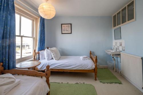 1 dormitorio con 2 camas, lavabo y ventana en Shore View, Aldeburgh - A lovely Seafront House on famous Crag Path with uninterrupted Beach Views - Aldeburgh Coastal Cottages, en Aldeburgh