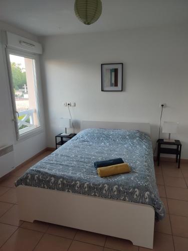 une chambre avec un lit avec une couverture bleue et une fenêtre dans l'établissement Appartement T2 avec balcon, centre de Castelnau de Médoc, à Castelnau-de-Médoc
