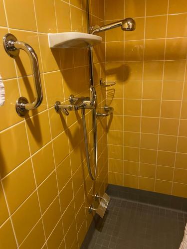 a yellow tiled bathroom with a shower and a sink at Igoumenitsa heart flats to let Mariasroom studios appart seaside-city Spyropoulos in Igoumenitsa