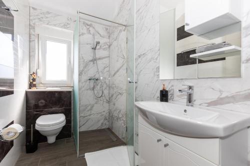 a white bathroom with a sink and a toilet at Villa Mare in Klek