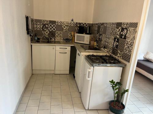 une petite cuisine avec une cuisinière et un micro-ondes dans l'établissement T2 proche des plages, à Sète