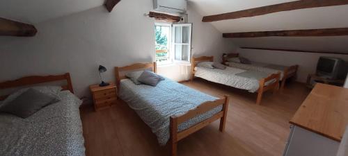 a room with three beds and a tv and a window at Le Jas des Sagnières - Un Gite de Charme en Haute Provence in Sigoyer