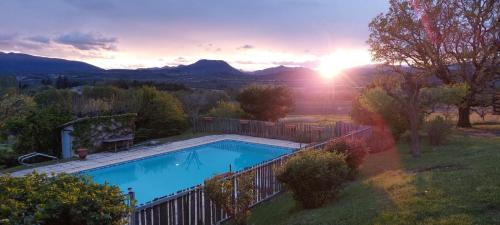 a swimming pool in a yard with the sunset in the background at Le Jas des Sagnières - Un Gite de Charme en Haute Provence in Sigoyer