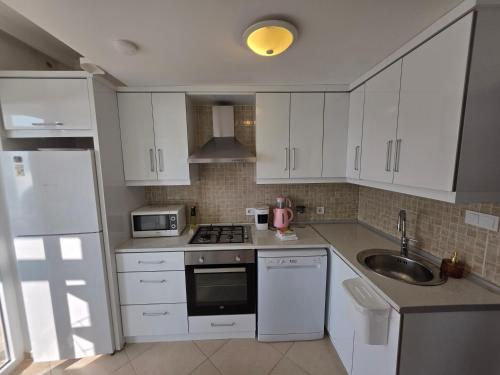 a kitchen with white cabinets and a sink at Sevinc Akasya Luxury Villa in Milas