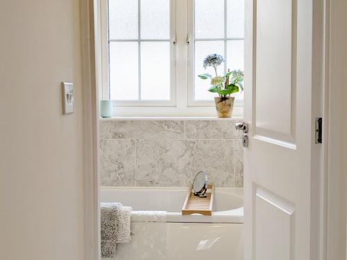 a bathroom with a tub and a window and a sink at Oysters in West Wittering