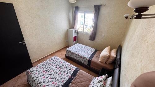 a small room with two beds and a window at Capo-martil Riviera residence three piscine in Cabo Negro