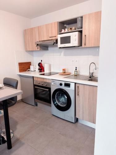 a kitchen with a washing machine and a microwave at L'Occitan T2 à 10 minutes du cœur de Toulouse Parking privé et Métro in Toulouse