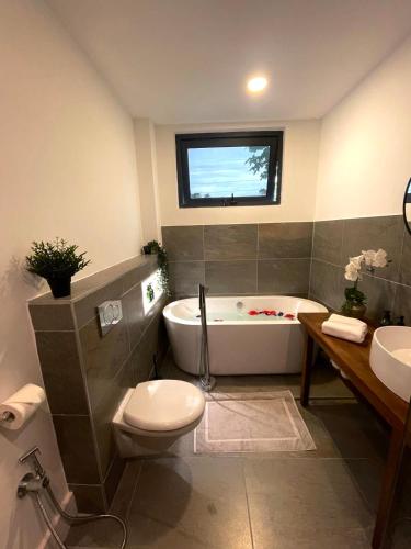 a bathroom with a tub and a toilet and a sink at Lulu Diani in Diani Beach